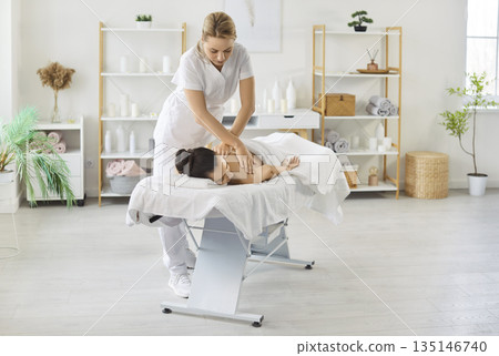 Masseuse Performing Back Massage In Salon 135146740