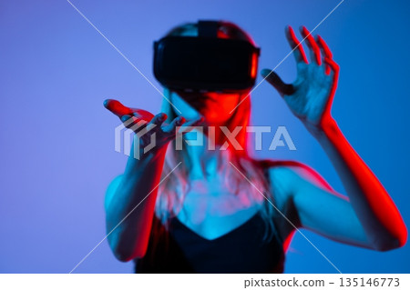 Woman Interacting With Virtual Reality Interface in Neon Light, Futuristic Metaverse Experience and Digital Technology Concept Woman Interacting With Virtual Reality Interface in Neon Light, Futuristic Metaverse Experience and Digital Technology Concept 135146773