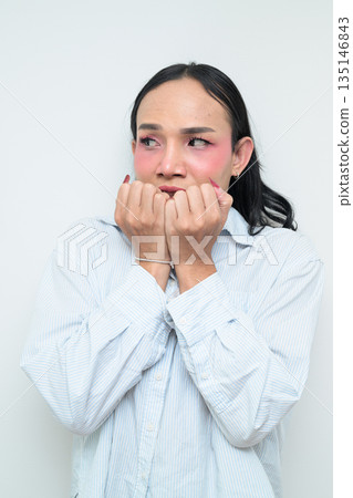Portrait of a young scared Thai transgender person biting nails against white background Portrait of a young scared Thai transgender person biting nails against white background 135146843