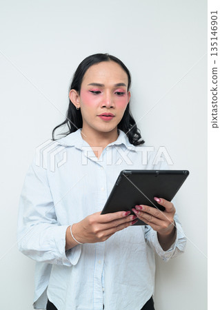 Portrait of a young Thai transgender person using digital tablet computer against white background Portrait of a young Thai transgender person using digital tablet computer against white background 135146901