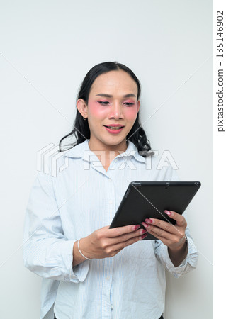 Portrait of a young Thai transgender person using digital tablet computer against white background Portrait of a young Thai transgender person using digital tablet computer against white background 135146902