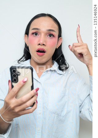 Portrait of a young Thai transgender person using phone against white background Portrait of a young Thai transgender person using phone against white background 135146924