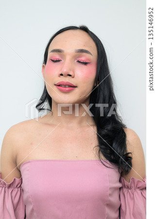Portrait of a young Thai transgender person against white background with eyes closed Portrait of a young Thai transgender person against white background with eyes closed 135146952