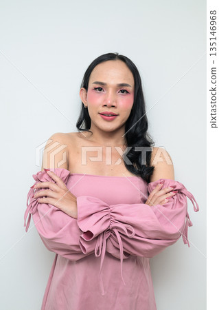 Portrait of a young Thai transgender person against white background with arms crossed smiling 135146968