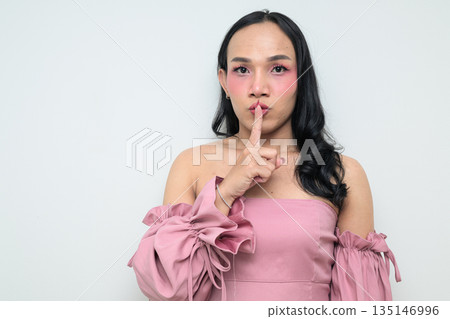 Portrait of a young Thai transgender person against white background with finger on lips Portrait of a young Thai transgender person against white background with finger on lips 135146996