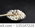 Organic tapioca pearls in black bowl on table. Spoon with white dry tapioca pearls, cooking ingredient, gluten free food, healthy eating. 135147228