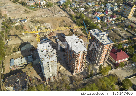 Apartment or office tall buildings under construction, top view. Tower cranes on city landscape background. Drone aerial photography. Apartment or office tall buildings under construction, top view. Tower cranes on city landscape background. Drone aerial photography. 135147400