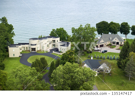 American dream homes on Ontario lakeshore as example of real estate development in US suburbs. View from above of waterfront residential houses in living area in Rochester, NY American dream homes on Ontario lakeshore as example of real estate development in US suburbs. View from above of waterfront residential houses in living area in Rochester, NY 135147417