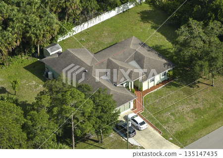 Aerial view of typical contemporary american private house with roof top covered with asphalt shingles and green lawn on yard Aerial view of typical contemporary american private house with roof top covered with asphalt shingles and green lawn on yard 135147435
