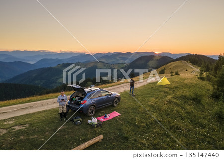 Aerial view of tourist camping tents and off road car on mountain campsite at bright sunny evening. Active tourism and offroad driving adventure concept 135147440