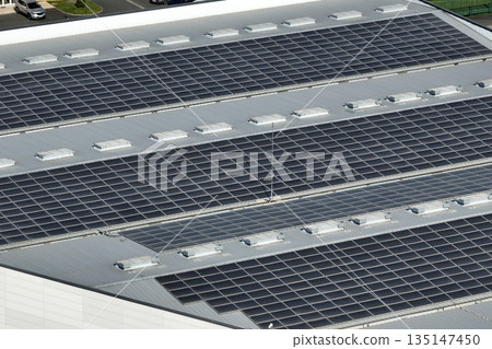 Aerial view of solar power plant with blue photovoltaic panels mounted on industrial building roof for producing green ecological electricity. Production of sustainable energy concept Aerial view of solar power plant with blue photovoltaic panels mounted on industrial building roof for producing green ecological electricity. Production of sustainable energy concept 135147450
