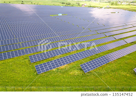 Aerial view of solar power plant on green field. Electric panels for producing clean ecologic energy. Aerial view of solar power plant on green field. Electric panels for producing clean ecologic energy. 135147452