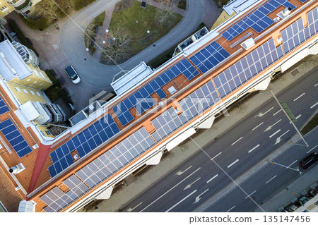 Aerial view of solar photo voltaic panels system on apartment building roof. Renewable ecological green energy production concept. Aerial view of solar photo voltaic panels system on apartment building roof. Renewable ecological green energy production concept. 135147456