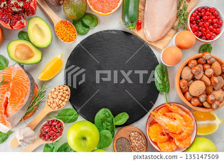 Healthy food ingredients frame with salmon shrimp chicken vegetables fruits and nuts around black slate plate with copy space Healthy food ingredients frame with salmon shrimp chicken vegetables fruits and nuts around black slate plate with copy space 135147509