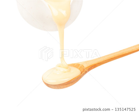 Condensed milk pouring into wooden spoon isolated on white background, sweet dairy dessert ingredient concept Condensed milk pouring into wooden spoon isolated on white background, sweet dairy dessert ingredient concept 135147525