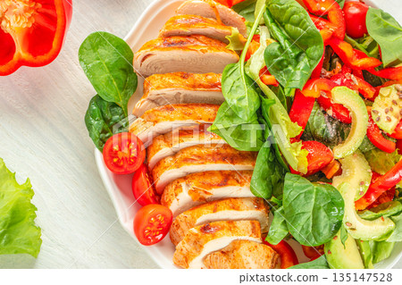 Sliced grilled chicken breast with fresh vegetable salad on white plate Sliced grilled chicken breast with fresh vegetable salad on white plate 135147528