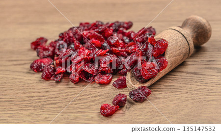 Dried cranberries spilled from wooden scoop on rustic wooden table Dried cranberries spilled from wooden scoop on rustic wooden table 135147532