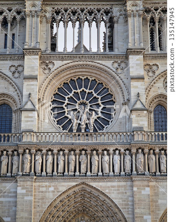 The intricate facade of Notre-Dame de Paris, with the massive rose window and the a row of statues below representing the Kings of Judah. Gothic architecture with delicate stone tracery and carvings 135147945