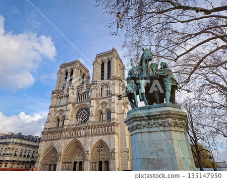Paris, France - December 10, 2025: Low-angle view of the Notre-Dame Cathedral in Paris and the bronze Charlemagne and his Guards statue stands prominently against the iconic twin towers Paris, France - December 10, 2025: Low-angle view of the Notre-Dame Cathedral in Paris and the bronze Charlemagne and his Guards statue stands prominently against the iconic twin towers 135147950