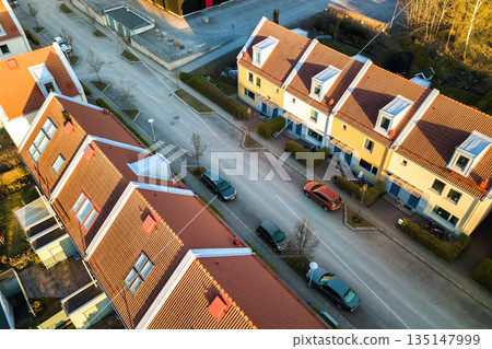 Aerial view of residential houses with red roofs and streets with parked cars in rural town area. Quiet suburbs of a modern european city. Aerial view of residential houses with red roofs and streets with parked cars in rural town area. Quiet suburbs of a modern european city. 135147999