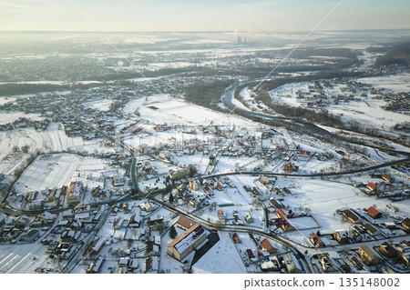 Aerial view of private homes with snow covered roofs in rural suburbs town area in cold winter Aerial view of private homes with snow covered roofs in rural suburbs town area in cold winter 135148002