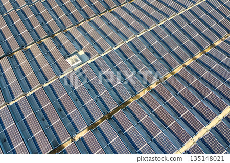 Aerial view of many photo voltaic solar panels mounted of industrial building roof. 135148021