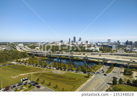 Aerial view of Jacksonville city with high office buildings and american freeway intersection with fast moving cars and trucks. USA transportation infrastructure concept Aerial view of Jacksonville city with high office buildings and american freeway intersection with fast moving cars and trucks. USA transportation infrastructure concept 135148028