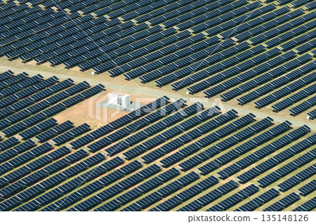 Aerial view of big sustainable electric power plant with many rows of solar photovoltaic panels for producing clean electrical energy. Renewable electricity with zero emission concept Aerial view of big sustainable electric power plant with many rows of solar photovoltaic panels for producing clean electrical energy. Renewable electricity with zero emission concept 135148126