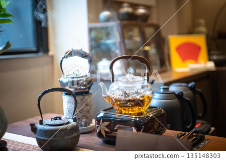 Elegant Kettle Boiling Tea With Flowers And Green Scenery Elegant Kettle Boiling Tea With Flowers And Green Scenery 135148303