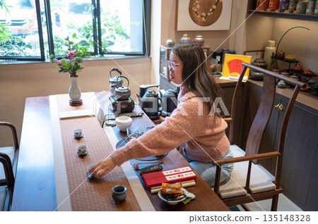 Female Tea Master Arranging Teacups On A Beautifully Set Tea Table 135148328