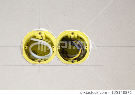 Two yellow electrical sockets installed in drywall 135148875