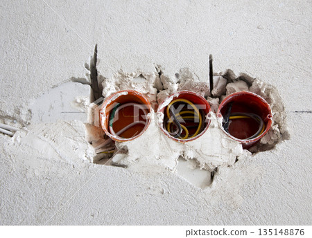 Three red electrical sockets installed in the brick wall 135148876