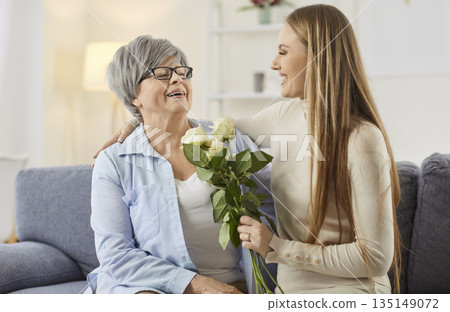 Loving female family care, young adult child congratulates elderly mother on birthday anniversary 135149072