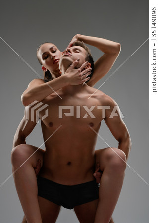 Sensual woman embracing a muscular man from behind in an artistic pose 135149096