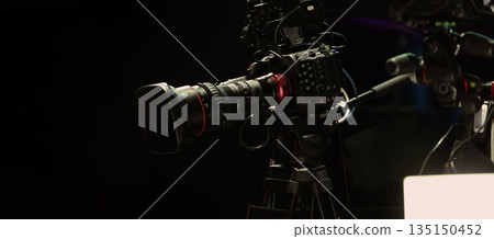 Behind the scenes of movie shooting or filming or video production with high quality camera and tripod equipment set up and professional film crew team in studio lighting. Video production camera gear Behind the scenes of movie shooting or filming or video production with high quality camera and tripod equipment set up and professional film crew team in studio lighting. Video production camera gear 135150452