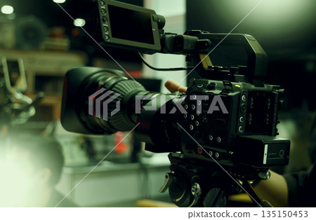 Behind the scenes of movie shooting or filming or video production with high quality camera and tripod equipment set up and professional film crew team in studio lighting. Video production camera gear 135150453
