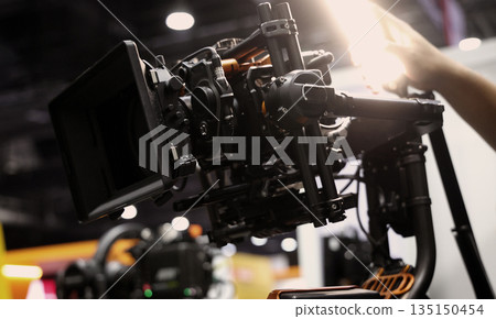 Behind the scenes of movie shooting or filming or video production with high quality camera and tripod equipment set up and professional film crew team in studio lighting. Video production camera gear 135150454