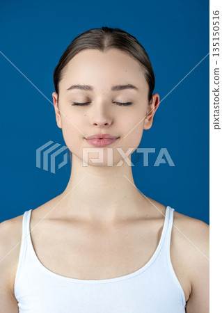 Young woman meditating with closed eyes on blue background Young woman meditating with closed eyes on blue background 135150516