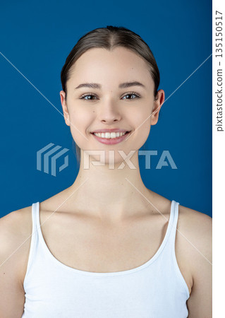 Smiling young woman against blue background looking at camera Smiling young woman against blue background looking at camera 135150517