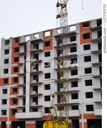 Tall apartment building under construction with crane. 135150538
