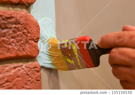 Outdoor wall painting by color brush. Handyman painting concrete block wall. 135150539