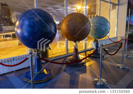 Decorative globes showcased with elegant lighting and setting, Sophisticated indoor exhibit featuring glowing globes with waterfront skyline backdrop and refined decor elements Decorative globes showcased with elegant lighting and setting, Sophisticated indoor exhibit featuring glowing globes with waterfront skyline backdrop and refined decor elements 135150560