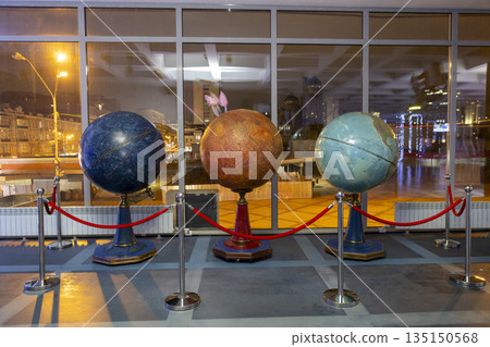 Decorative globes showcased with elegant lighting and setting, Sophisticated indoor exhibit featuring glowing globes with waterfront skyline backdrop and refined decor elements Decorative globes showcased with elegant lighting and setting, Sophisticated indoor exhibit featuring glowing globes with waterfront skyline backdrop and refined decor elements 135150568