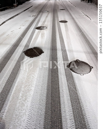 Tire marks on freshly fallen snow on a road at night 135150637