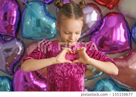 A girl shows a heart gesture with her hands on Valentine's day, congratulating on the holiday of lovers A girl shows a heart gesture with her hands on Valentine's day, congratulating on the holiday of lovers 135150677