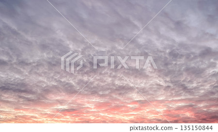 Dramatic sunset sky with textured clouds glowing in pink and orange colors during evening twilight 135150844