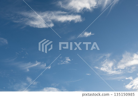 Wispy cirrus clouds drifting across a vibrant blue sky 135150985