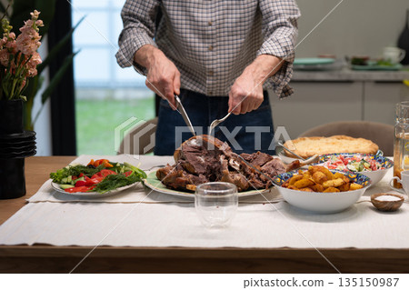 Man carving roasted meat for festive family dinner Man carving roasted meat for festive family dinner 135150987