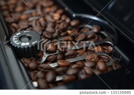 Coffee beans filling coffee machine container, ready for grinding Coffee beans filling coffee machine container, ready for grinding 135150990