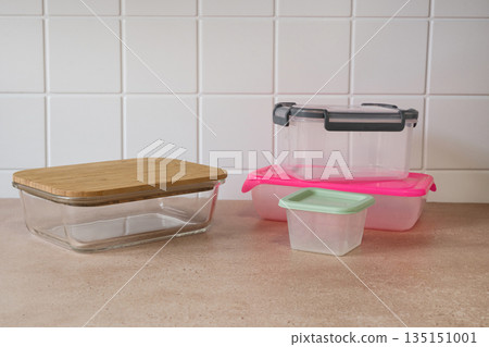 Plastic and glass food storage containers on kitchen countertop. Meal prep, organization, household storage, modern kitchen concept. Plastic and glass food storage containers on kitchen countertop. Meal prep, organization, household storage, modern kitchen concept. 135151001